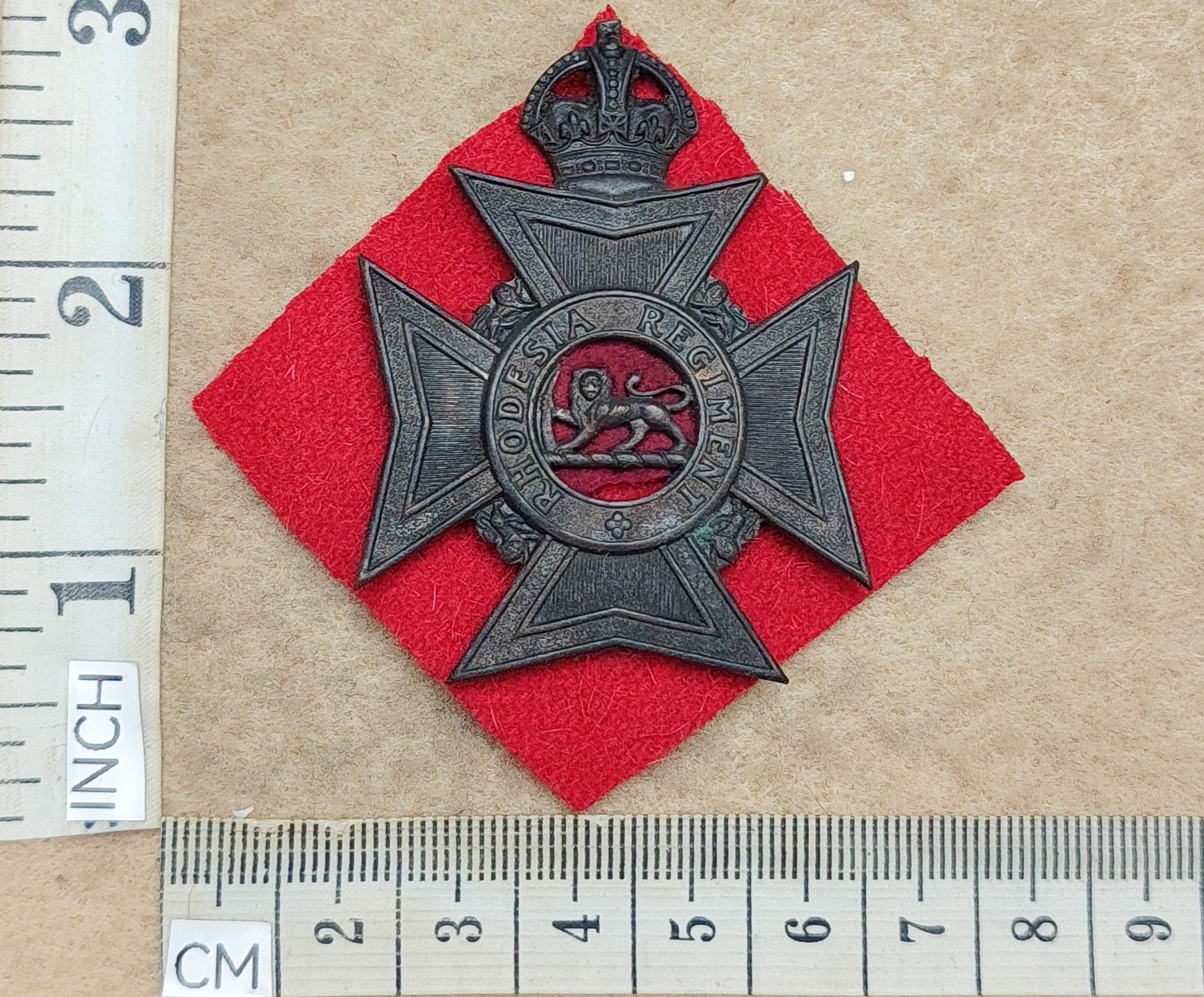 10719-3 Rhodesia Regiment helmet badge, large size, red flash backing (CO2990)